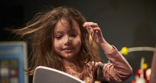 Jeune visiteuse expérimentant les effets de l’électricité statique au moyen du générateur de Van de Graaff.