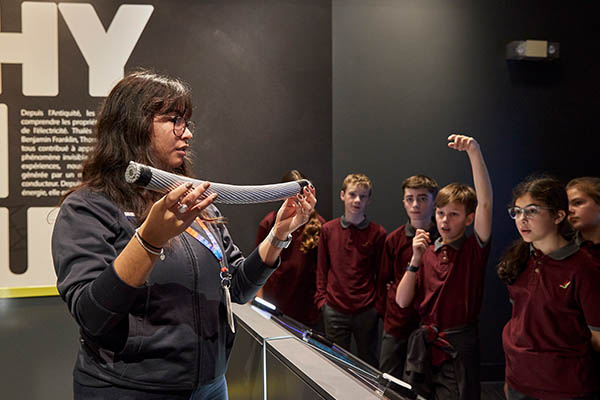 Guide présentant un morceau de câble électrique à des élèves en visite à l’Électrium.