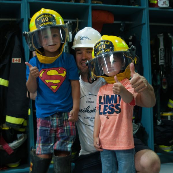 Père et enfants portant un casque de pompier.