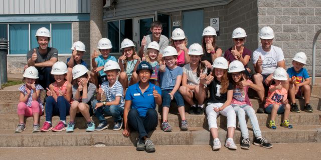 Guide et groupe scolaire à l’extérieur de la centrale des Îles-de-la-Madeleine.