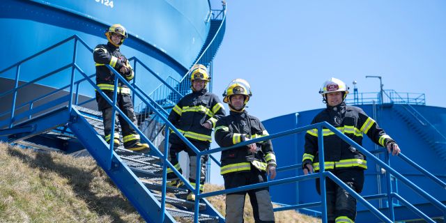 Pompiers volontaires devant un réservoir de carburant.