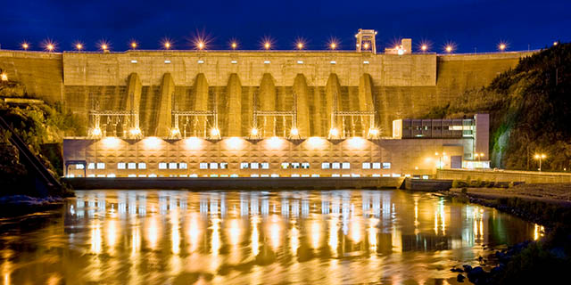 Vue nocturne aval du barrage et de la centrale éclairés.