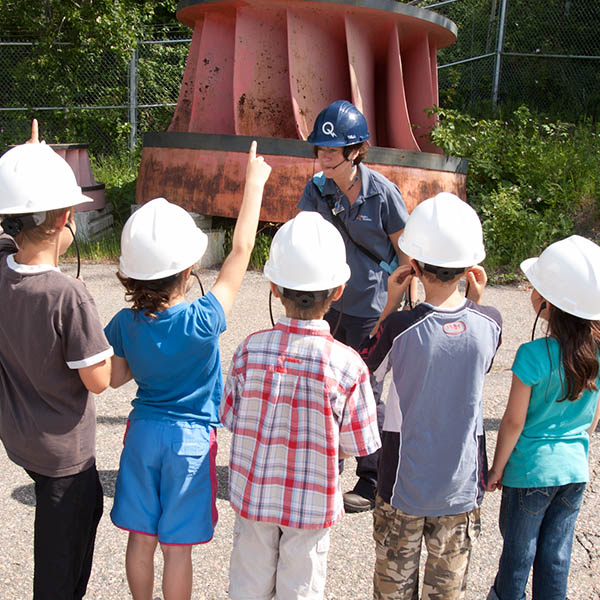 Enfants devant une ancienne turbine à l’extérieur de la centrale.
